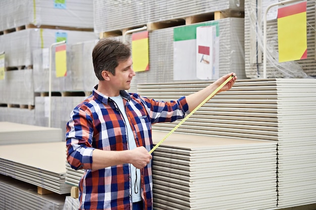 man measures with roulette drywall sheets store building materials 165146 707
